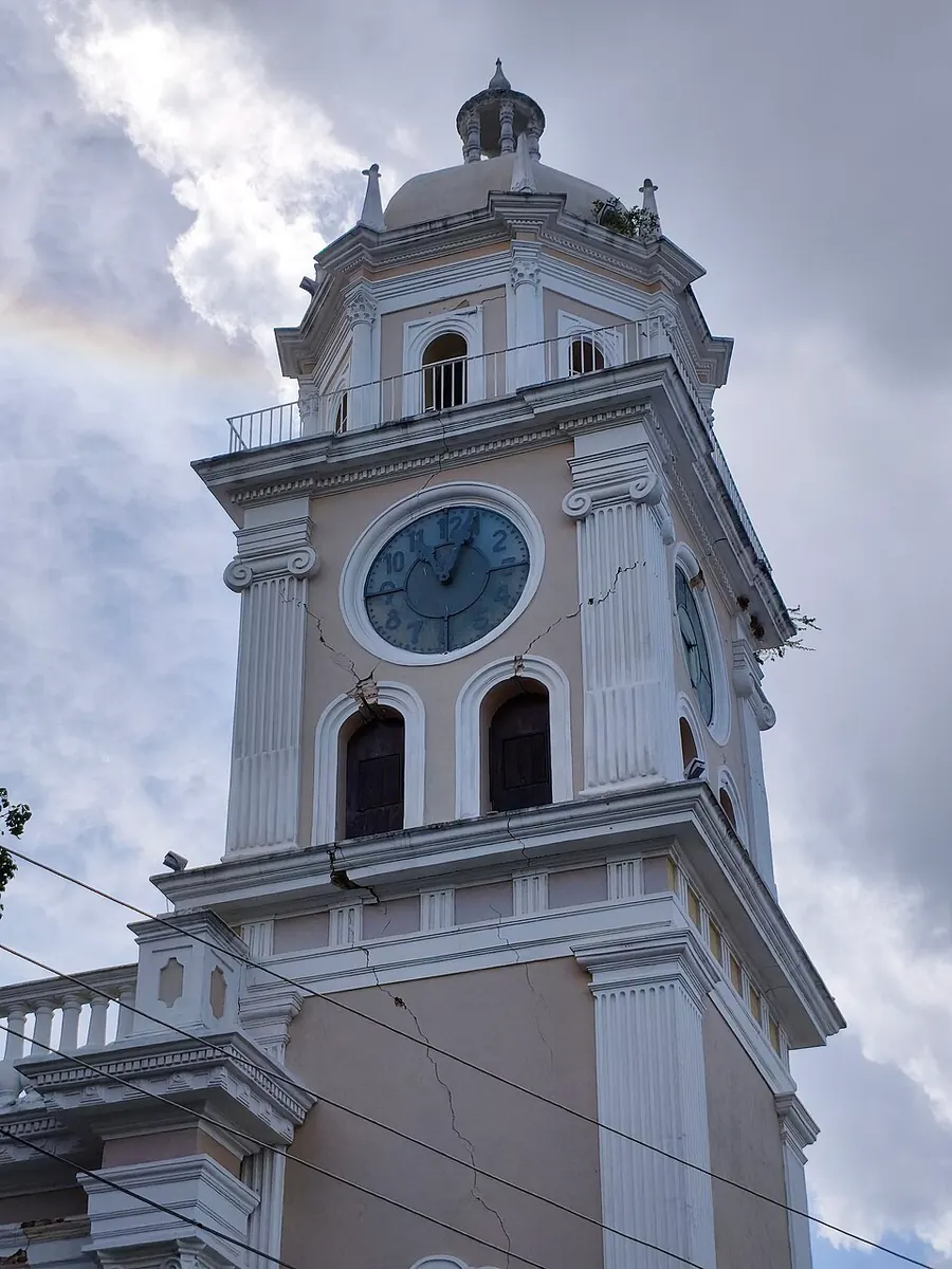 The clock tower of Valencia Cathedral seen from below, with cracks running diagonally down from the windows and along the cornices.