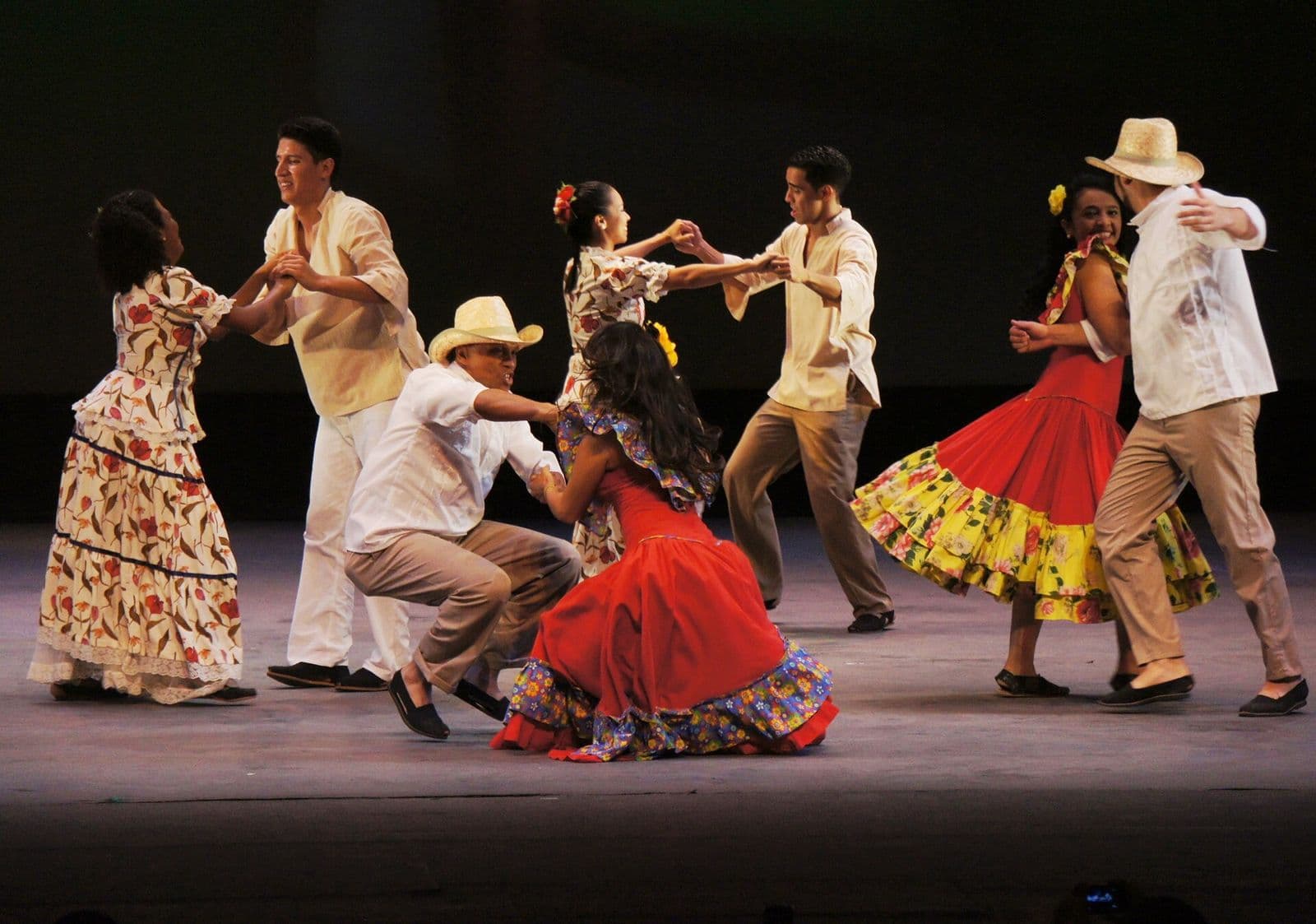 Couples in liquiliques (traditional men's suits) and flowered skirts dance golpe larense on a stage