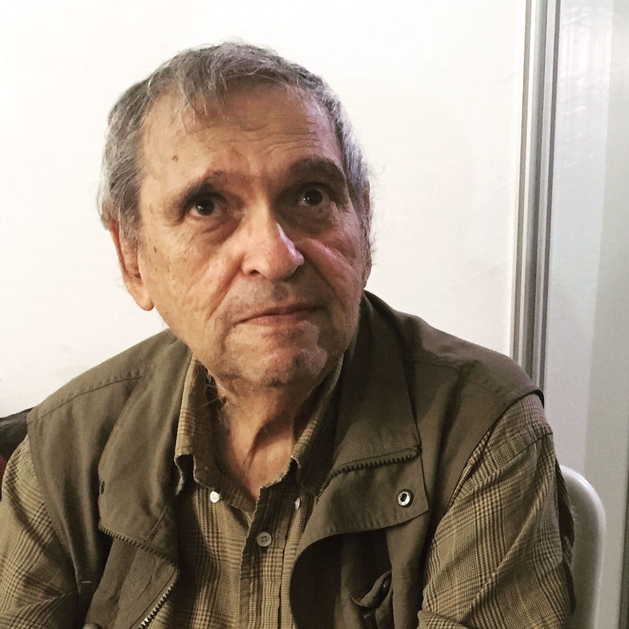 Portrait of the poet Rafael Cadenas, with gray hair and a green vest