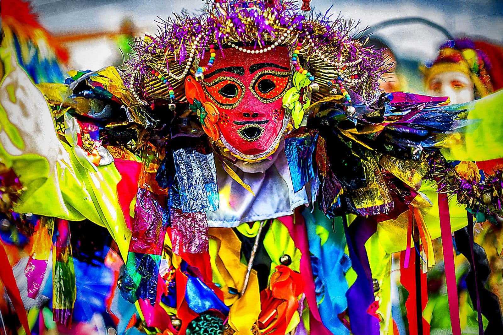A zaragoza dancer in a painted red mask and a bright patchwork costume dances in the plaza of Sanare